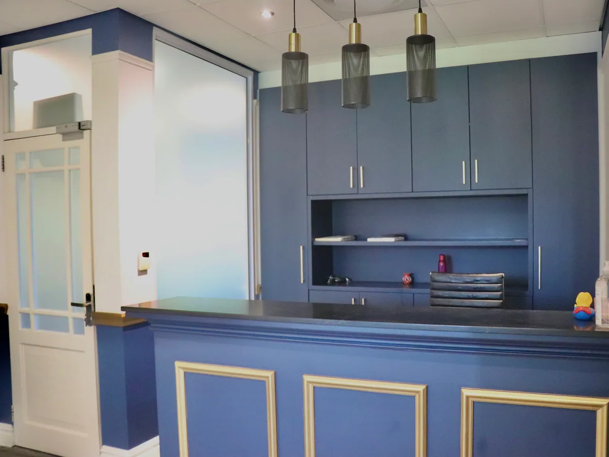 The Val de Vie reception desk: navy joinery with gold trim under three pendant lights.